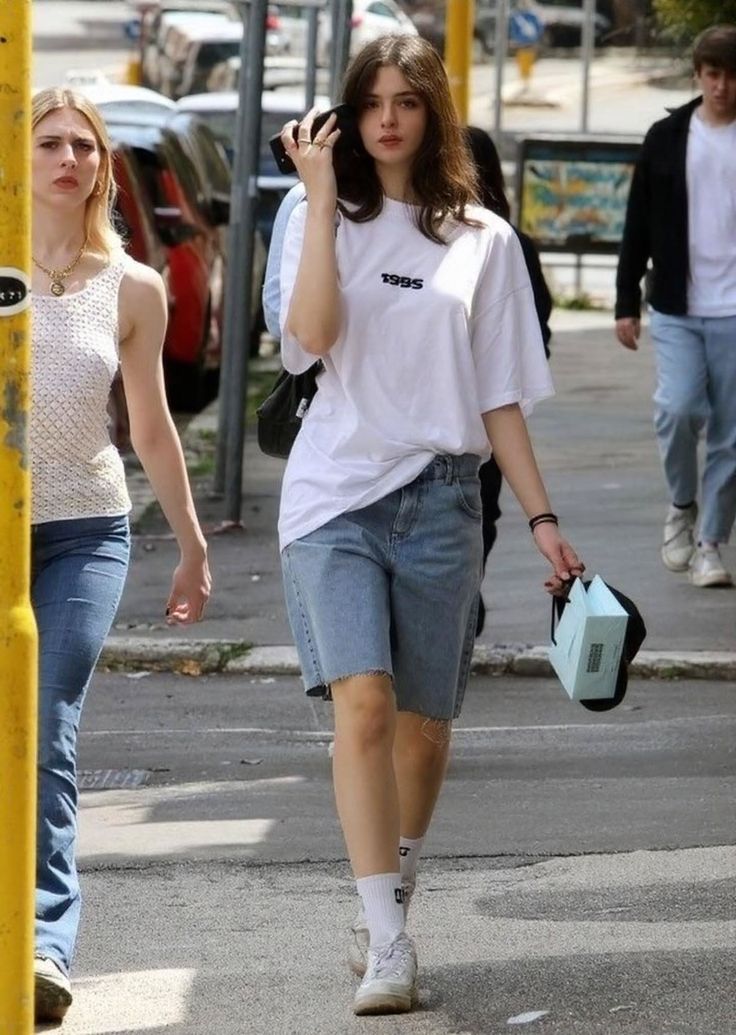 Young woman in a white t-shirt and denim shorts walking on a street