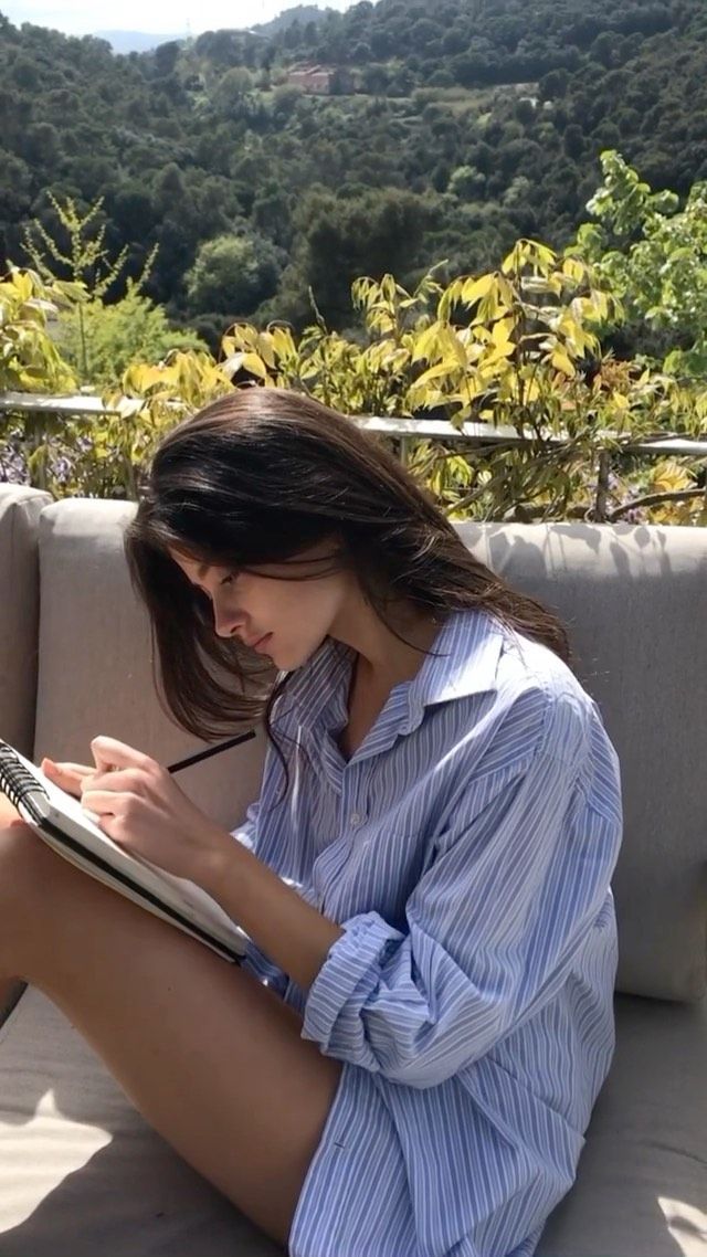 Woman with long hair drawing outdoors in a striped shirt