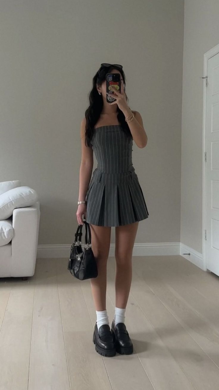 Woman in a pinstripe dress taking a mirror selfie indoors