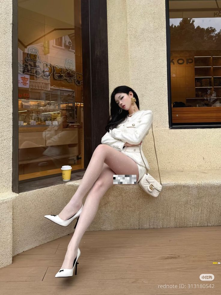 Woman in a white jacket and short skirt with polka dot stockings sitting outdoors
