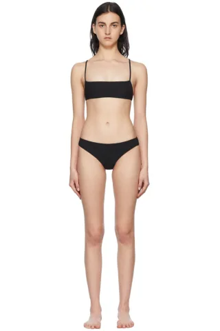 Woman in a black bikini standing against a white background