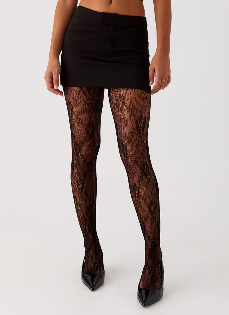 Person wearing a black mini skirt, lace tights, and high heels