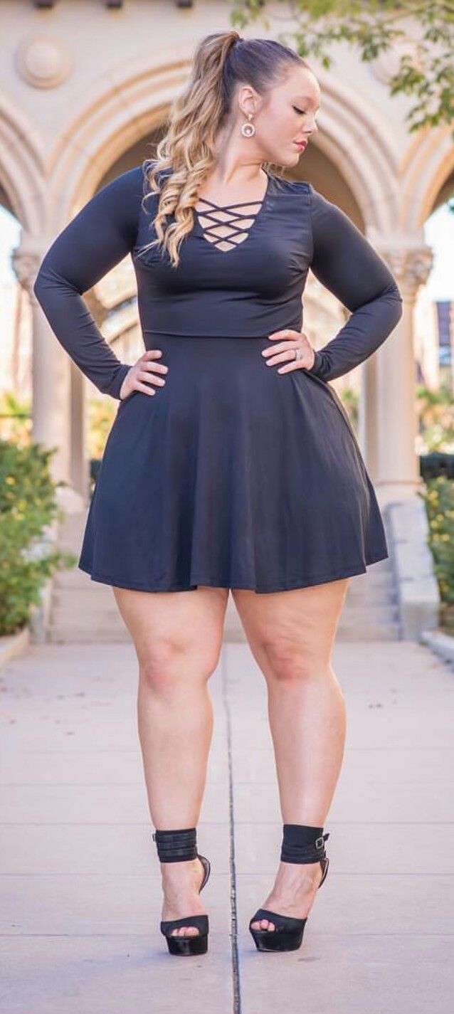 Woman in a black dress and high heels posing outdoors