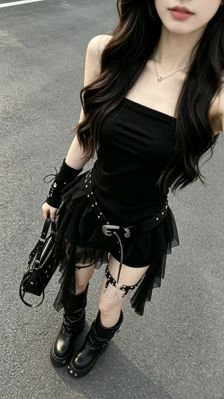 Woman in a black gothic-style dress with platform boots and leg harness outdoors