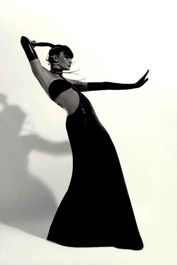 Woman in a black latex dress and futuristic headpiece posing dramatically