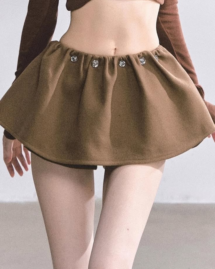 Person in a brown mini skirt and cropped top with exposed midriff