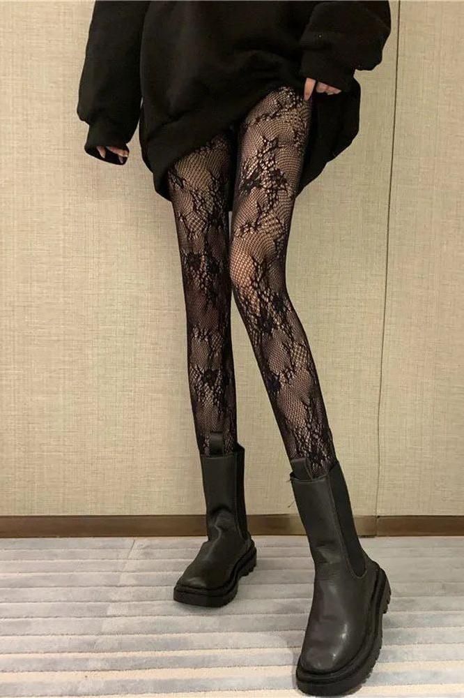 Person wearing lace tights and black boots with an oversized top indoors