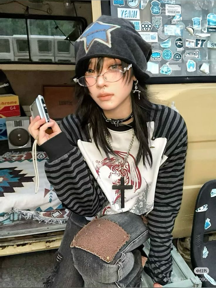 Person in a beanie and striped shirt holding a camera indoors
