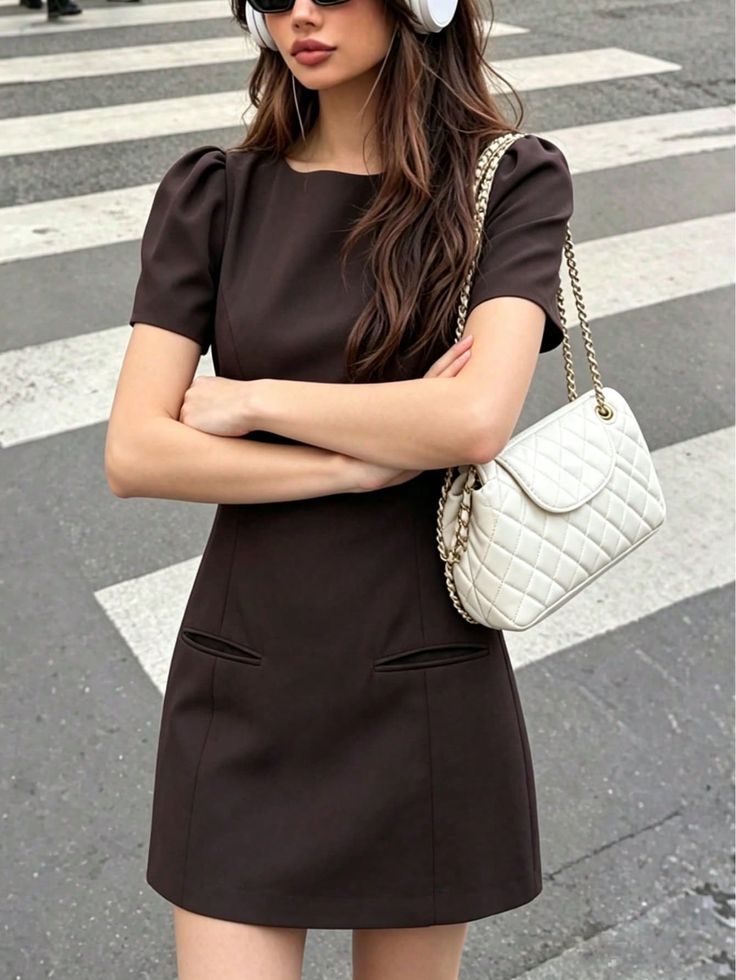Woman in a brown dress with sunglasses and headphones on a crosswalk