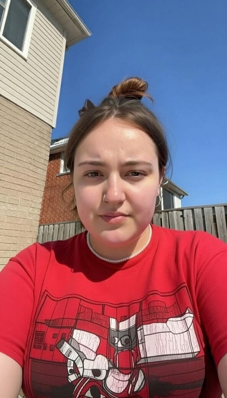Woman in a red t-shirt and pearl necklace outdoors on a sunny day