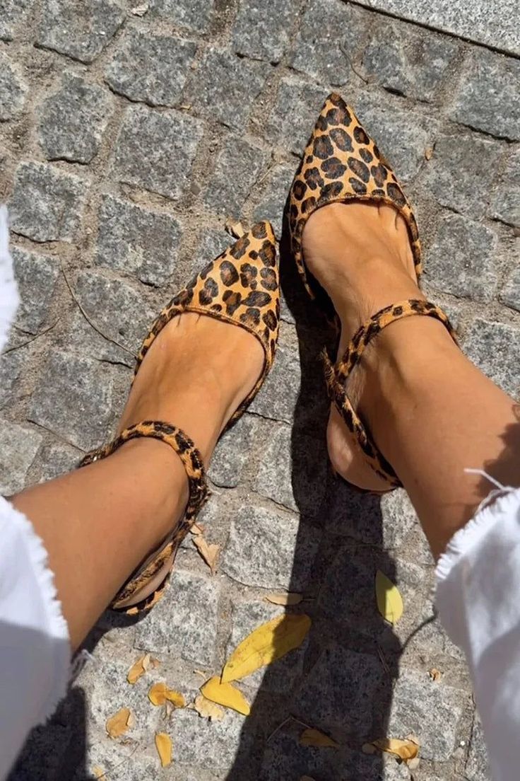 Person wearing leopard print flats on a cobblestone street with fallen leaves