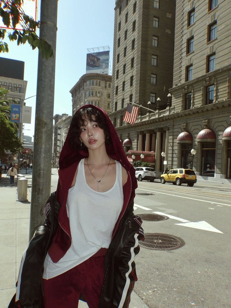 Person in a red hoodie and white tank top on a city street
