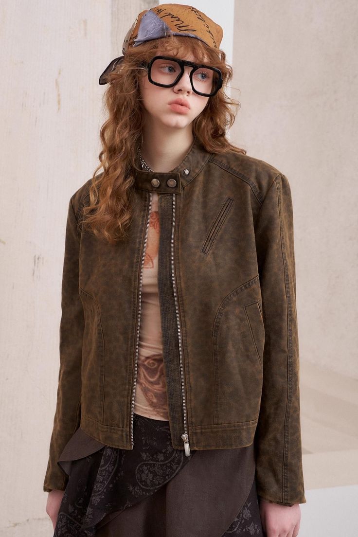 Woman with long curly hair, wearing a brown jacket, bandana, and glasses