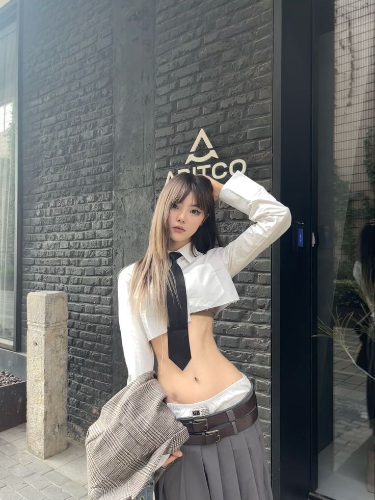 Woman in a cropped school uniform shirt and skirt posing outdoors