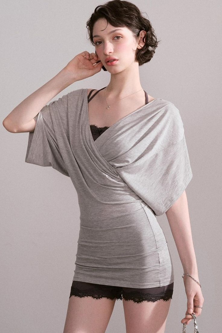 Woman with short hair wearing a gray top and black lace shorts