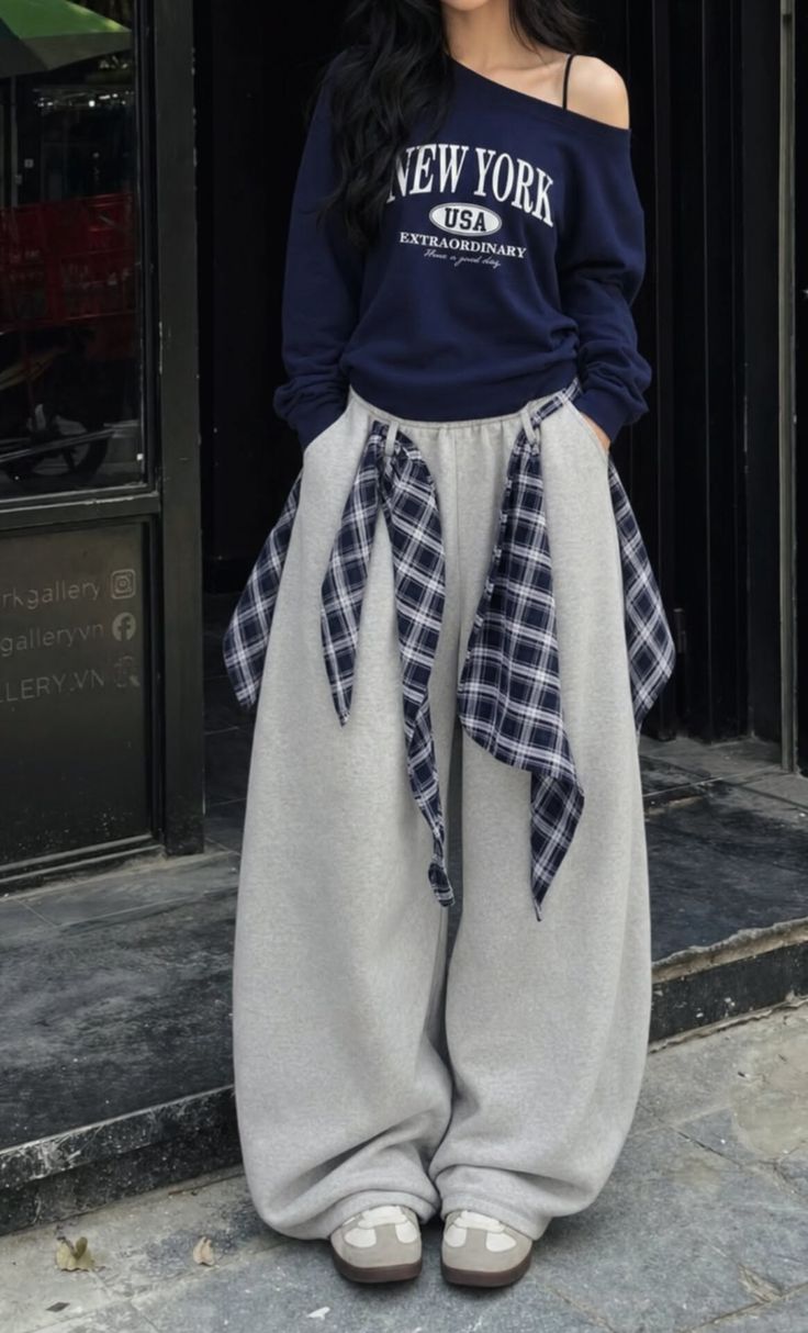 Person in an oversized sweatshirt and wide leg pants with plaid accents outdoors