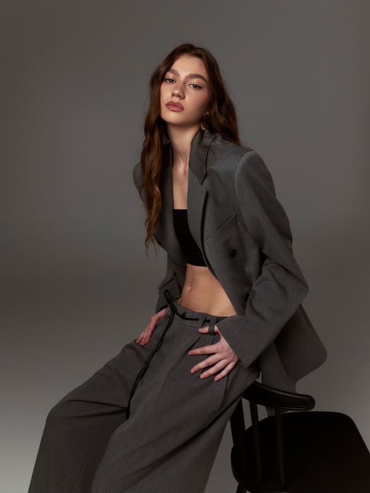 Woman in a gray suit jacket and black crop top in a studio