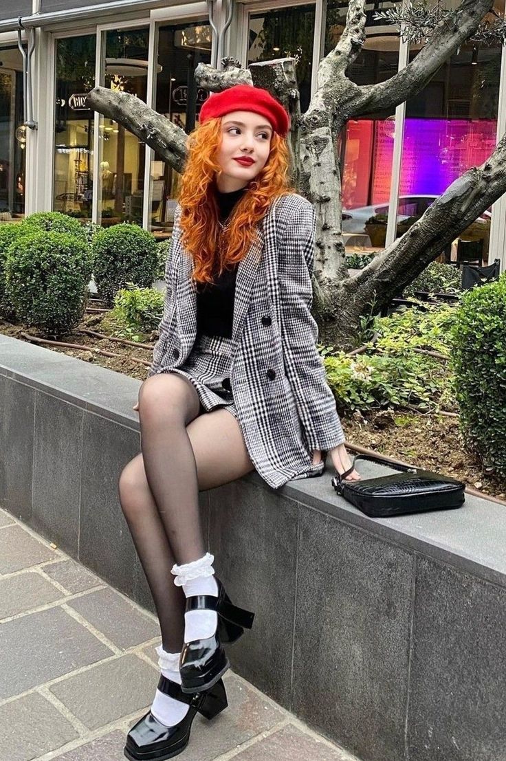 Woman with red curly hair wearing a plaid suit and red beret outdoors
