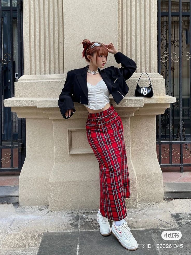 Woman in a red plaid skirt and cropped jacket posing outdoors