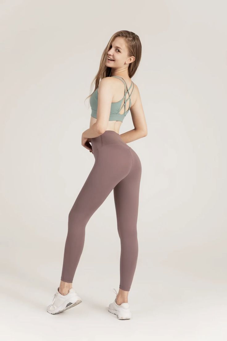 Woman in a sports bra and leggings posing in a studio