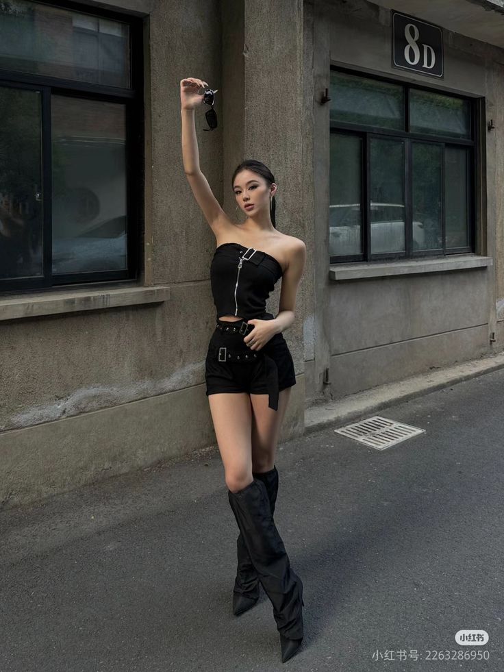 Woman in a black tube top and shorts with boots on a street