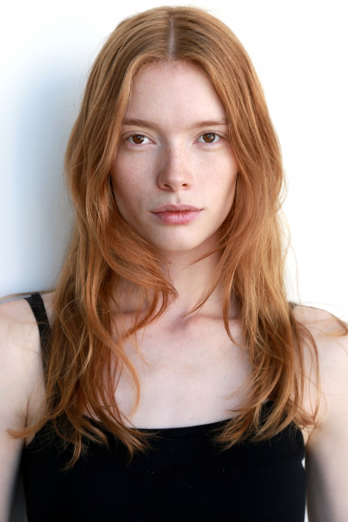 Woman with long red hair and freckles wearing a black top