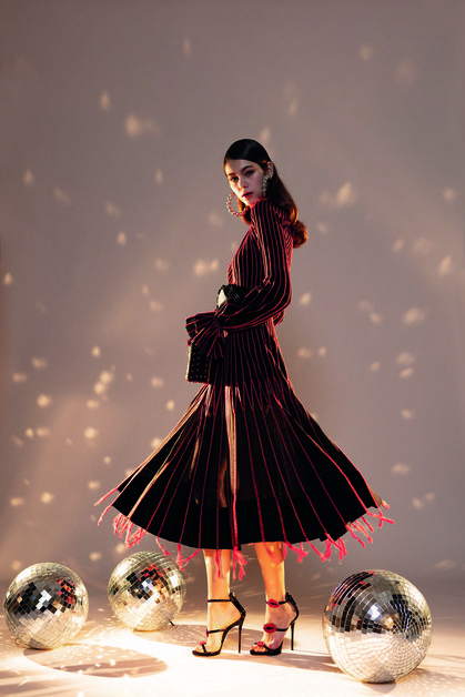 Woman in a long striped dress and high heels with disco balls on the floor
