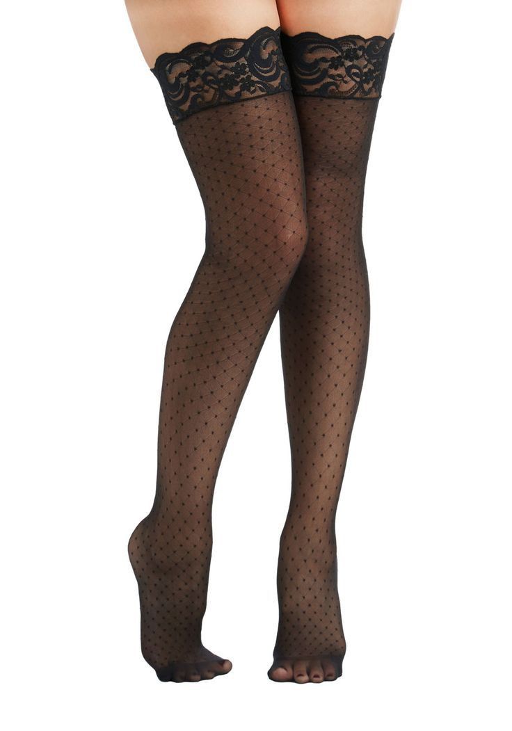 Pair of legs wearing black lace-top polka dot stockings