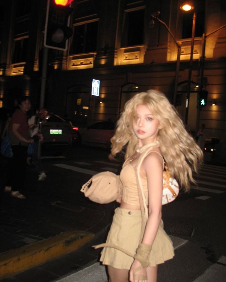 Blonde woman in a crop top and mini skirt on a city street at night