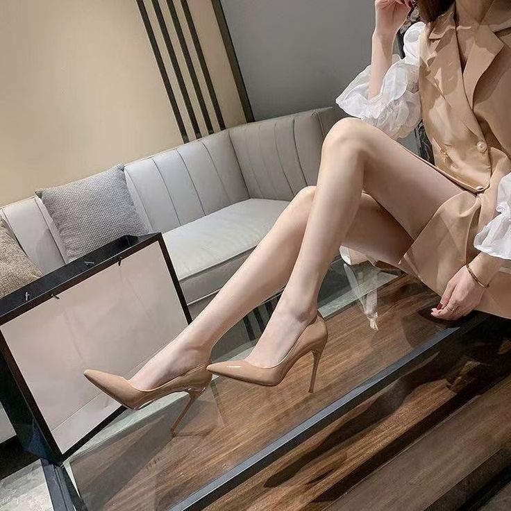 Woman in a blazer and high heels sitting indoors
