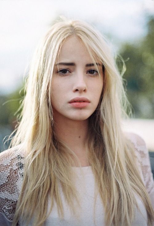 Woman with long blonde hair wearing a lace top outdoors