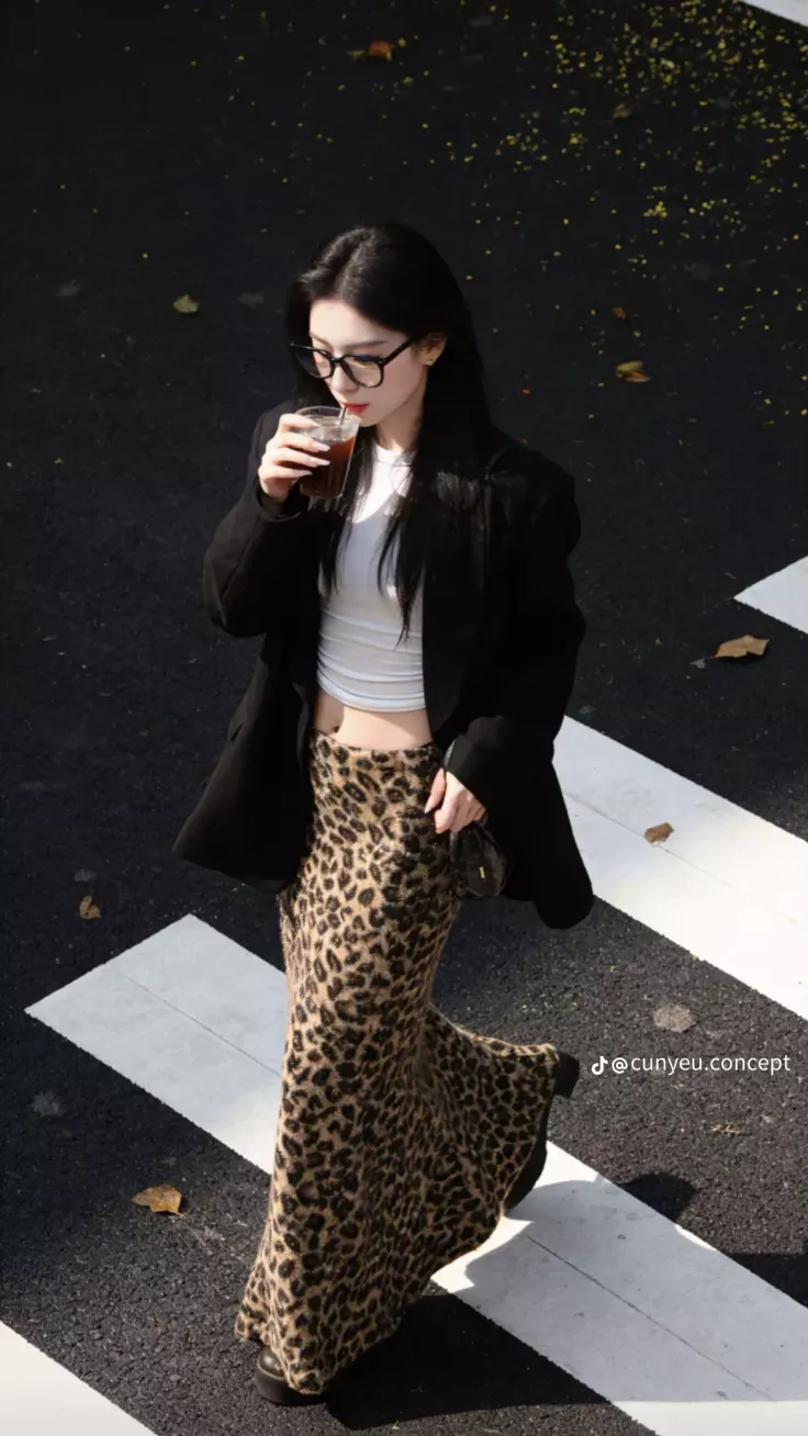 Woman in a leopard print skirt and crop top walking on a street