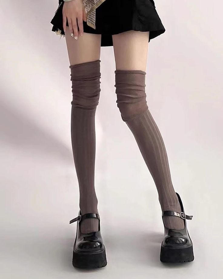 Person wearing a black mini skirt, brown thigh-high socks, and platform mary jane shoes
