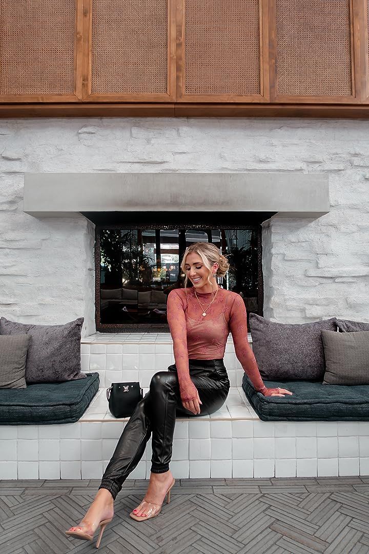 Woman in a sheer top and leather pants sitting on a tiled bench indoors