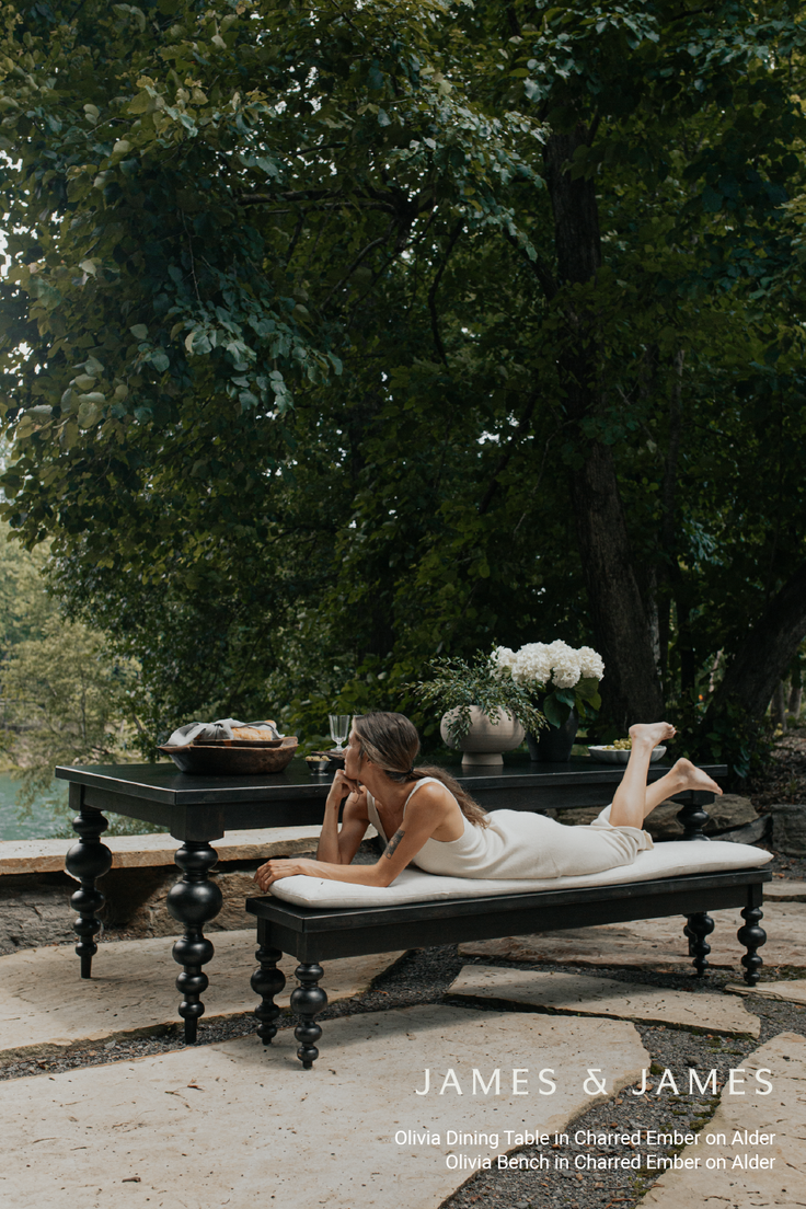 Woman in a white dress relaxing on an outdoor bench next to a dining table