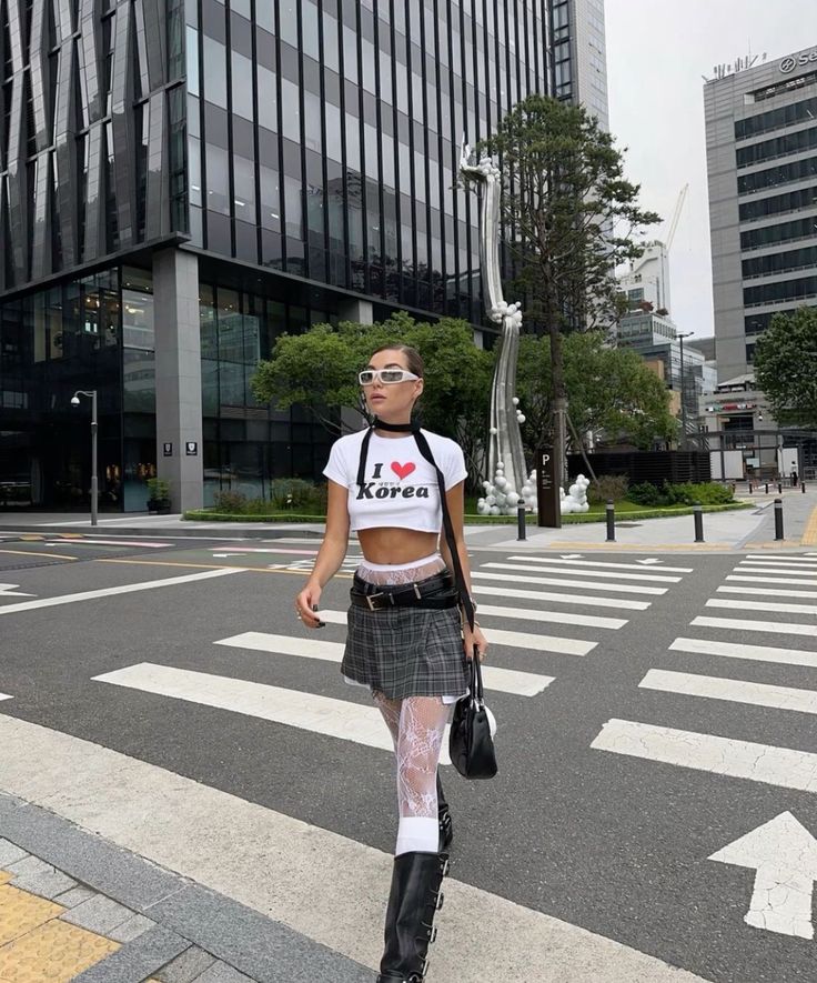 Woman in a crop top and plaid skirt walking on a city street