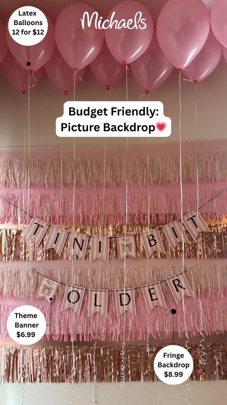 Pink and gold party decorations with balloons, fringe, and a banner