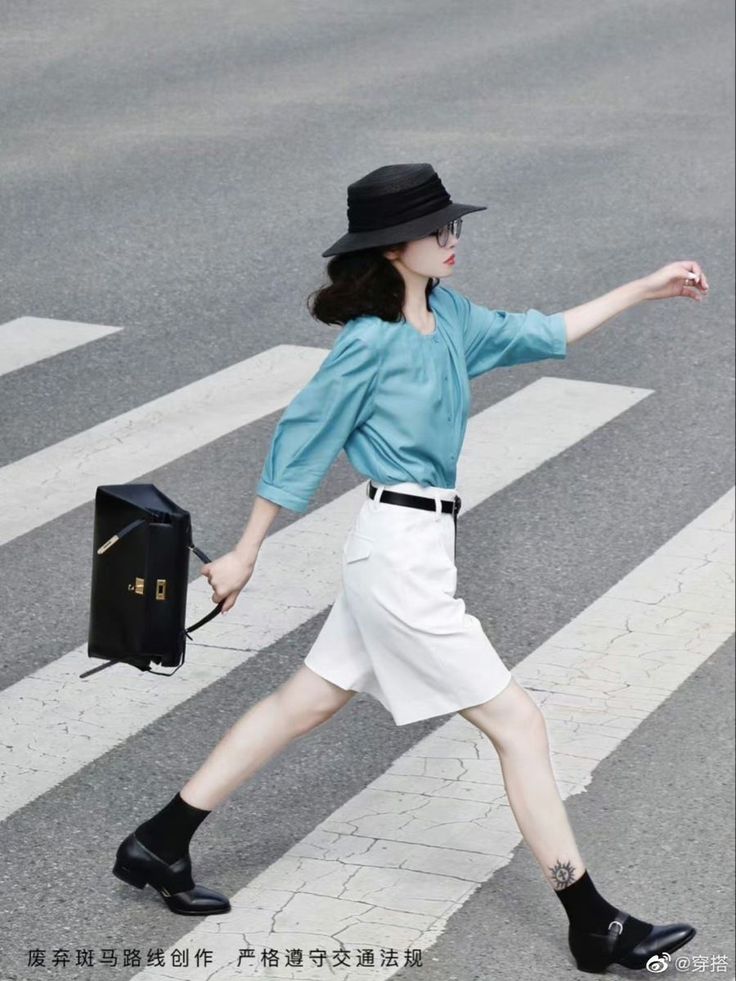 Woman in a black hat and blue shirt crossing a street on a crosswalk