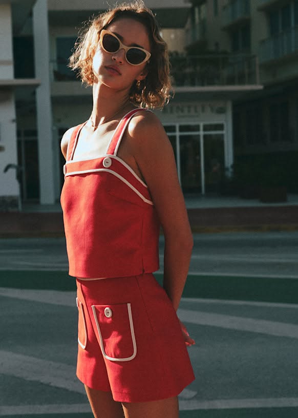 Woman in a red top and shorts with sunglasses outdoors