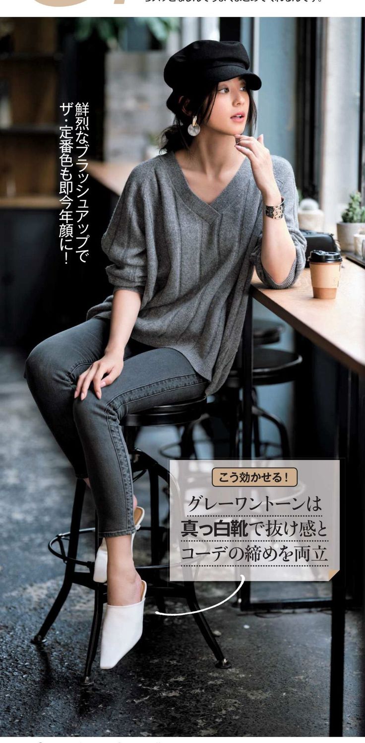 Woman in a black hat and gray outfit sitting at a cafe counter