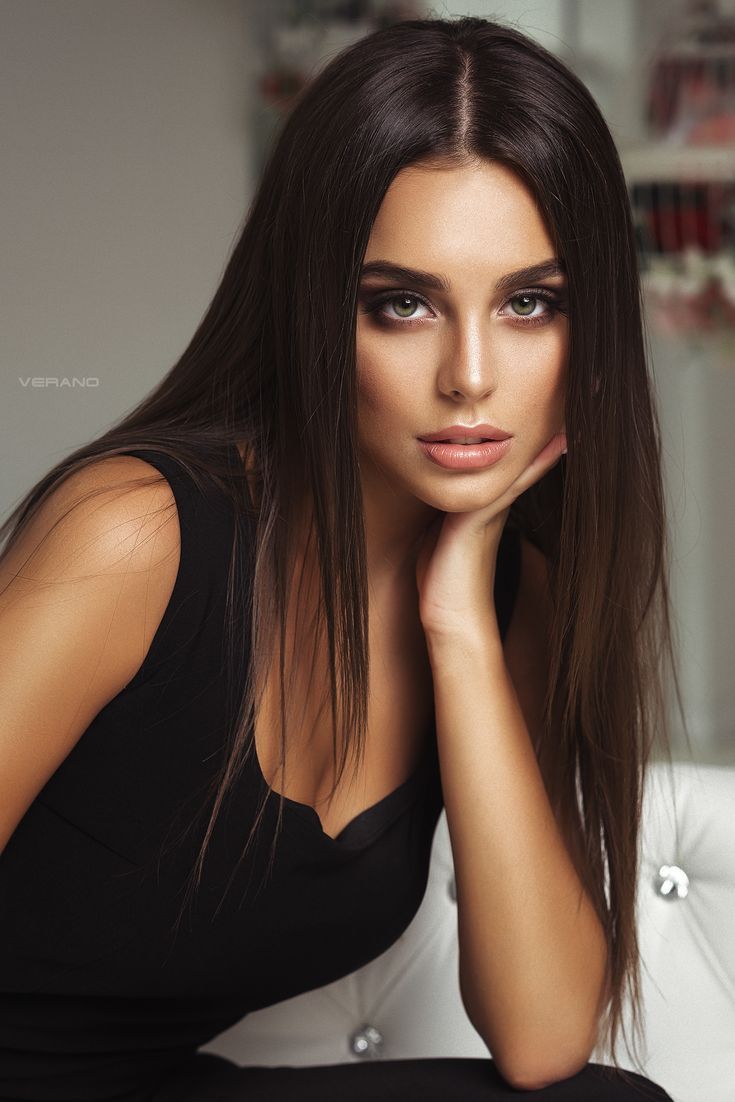 Woman with long dark hair and green eyes wearing a black top