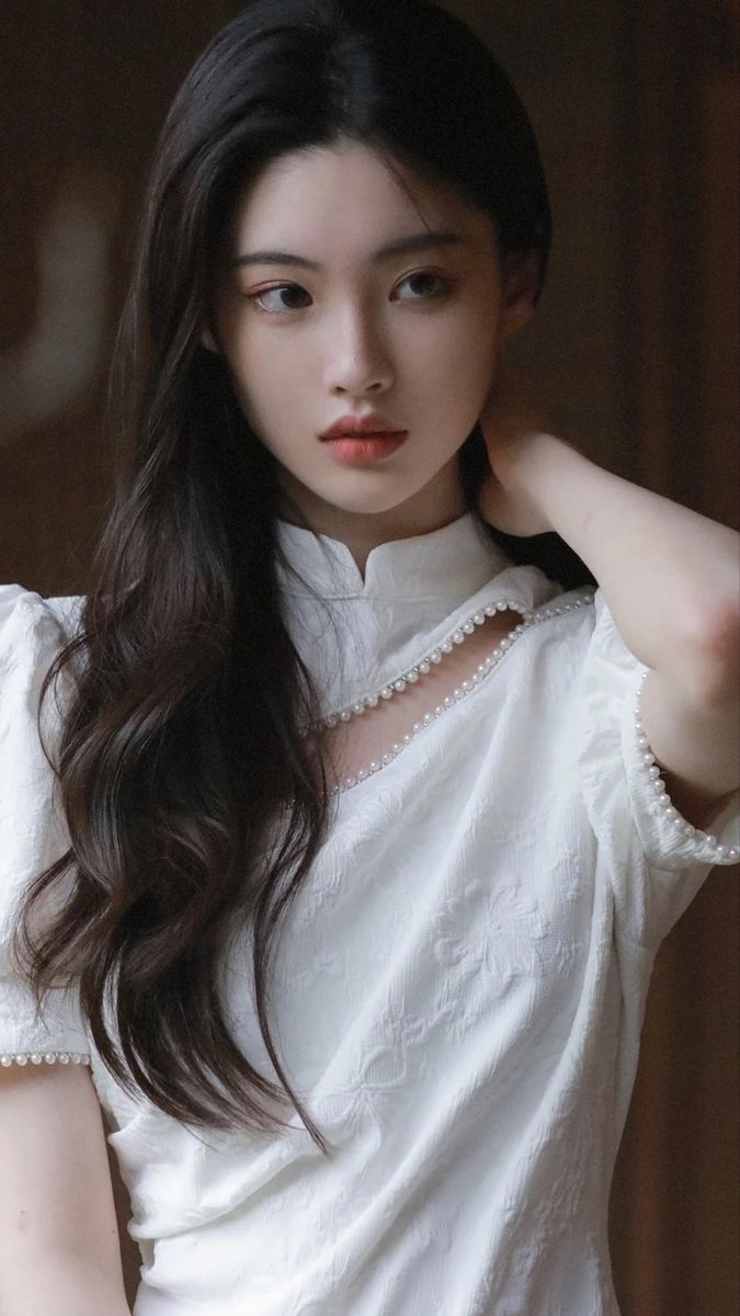 Woman with long dark hair in a white dress with pearl trim