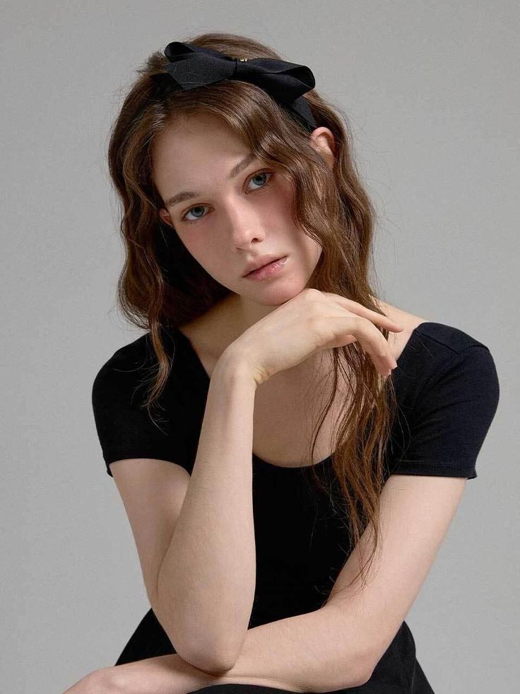 Woman with long wavy hair and a black headband in a studio setting