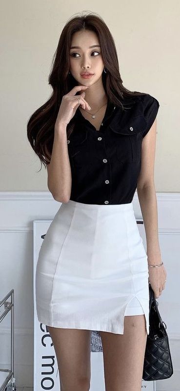 Woman with long hair wearing a black shirt and white mini skirt indoors