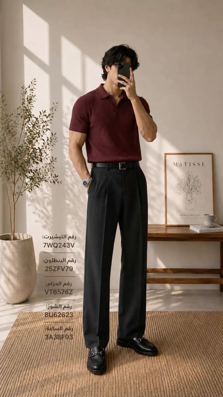 Man in a maroon polo shirt and black pants taking a mirror selfie indoors