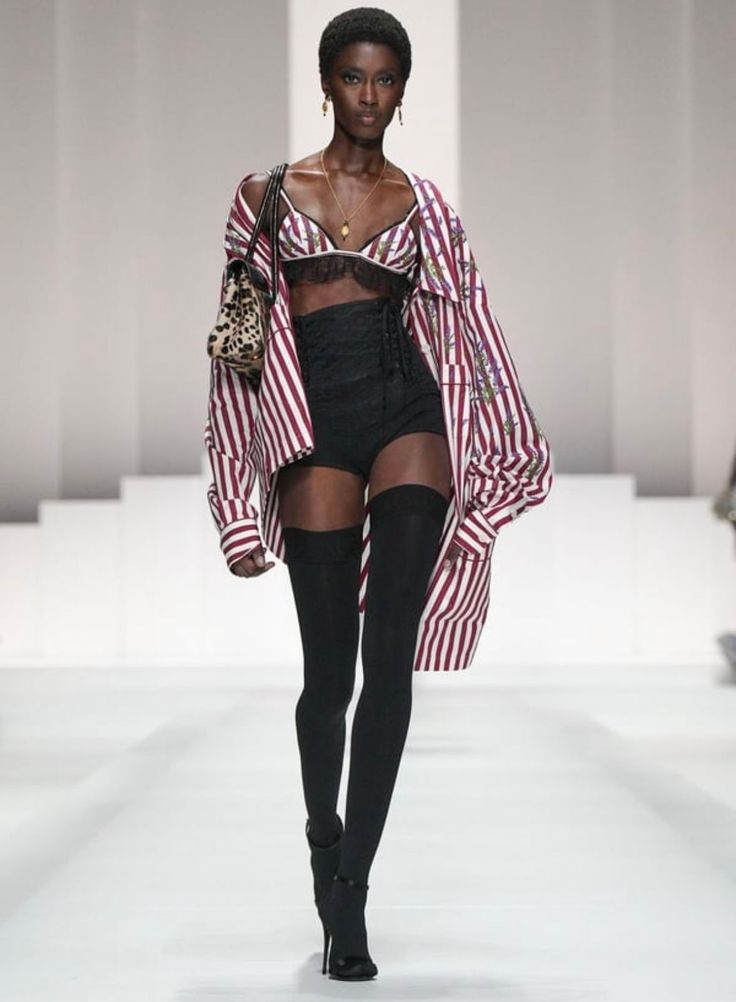 Runway model in a striped shirt, bra top, high waisted shorts, and thigh high stockings