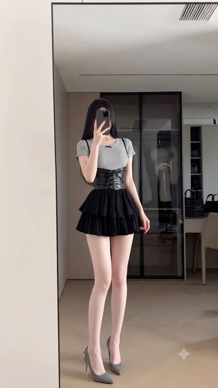 Woman in a black tiered skirt and corset top taking a mirror selfie