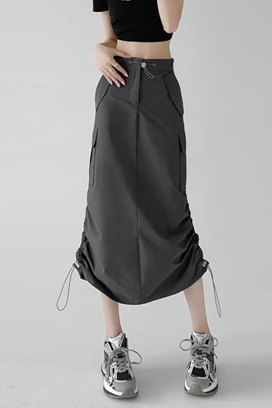 Person wearing a black crop top and a dark grey cargo skirt with sneakers