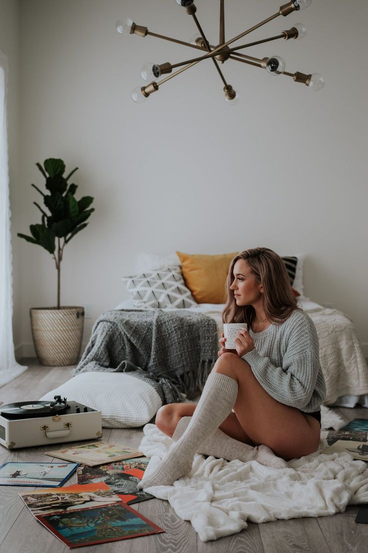 Woman in a chunky knit sweater and knee high socks sitting on the floor