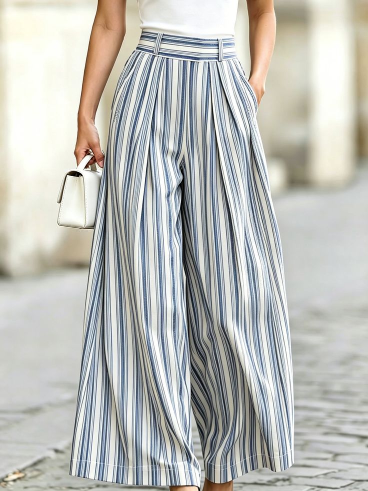 Person wearing striped wide-leg pants and a white top, holding a white handbag